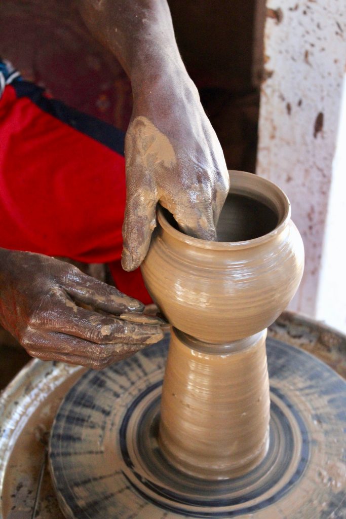 person making clay pottery on a pottery wheel
