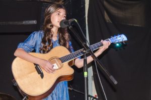 woman singing and playing acoustic guitar