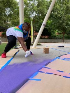 Artist Darlene J. McClinton spray painting a mural