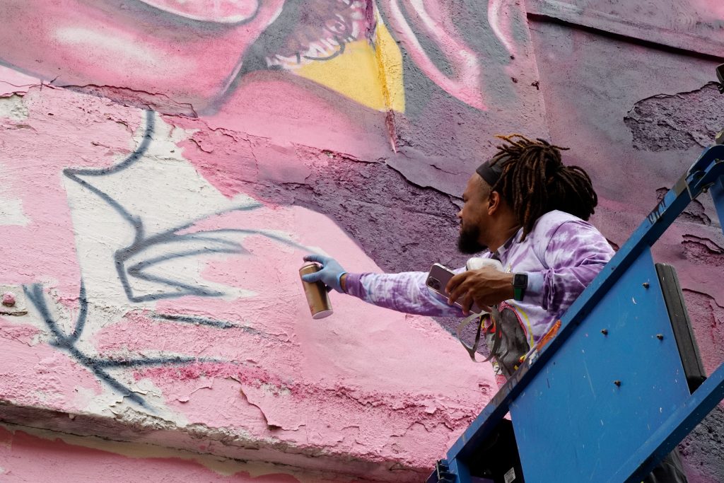 a man spray painting th eside of a brick building