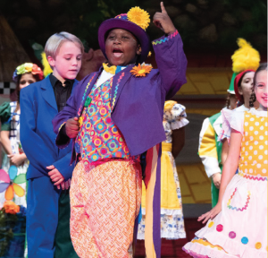 Children perform on stage in a theater production.